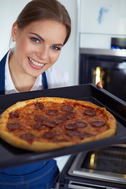 Glückliche junge Frau, die zu Hause Pizza kocht