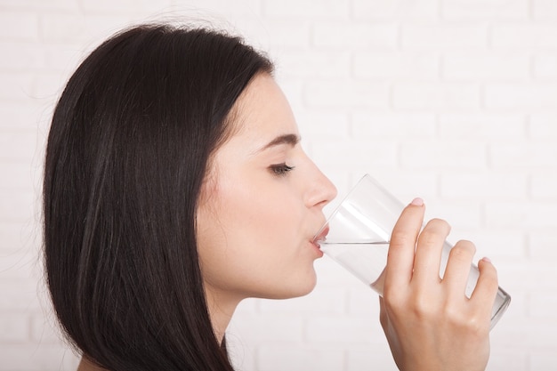 Glückliche junge Frau, die zu Hause Wasser trinkt