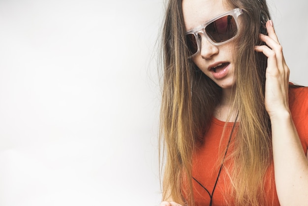 Glückliche junge Frau, die zuhört, langes Haar, coole Sonnenbrille. Frau mit Kopfhörern und Brille