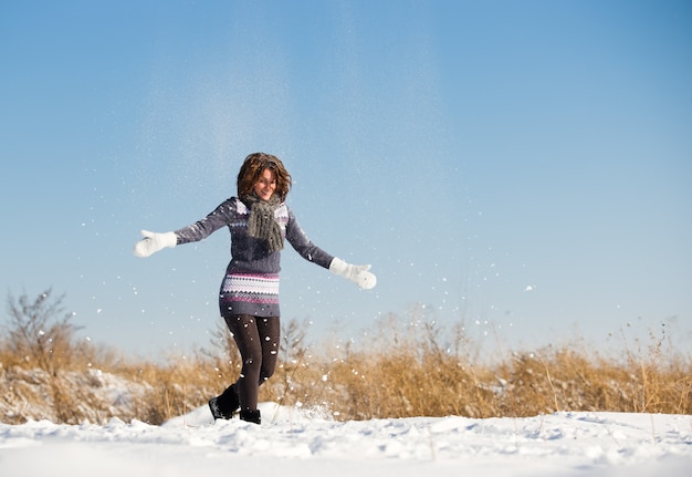 Glückliche junge Frau haben Spaß und genießen frischen Schnee am schönen Wintertag