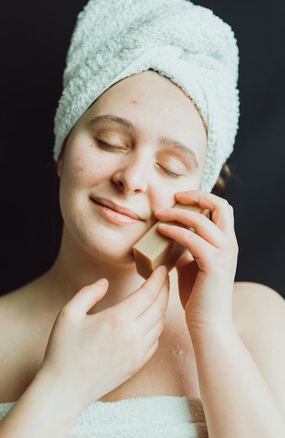 Glückliche junge Frau hält ein Stück Naturseife in der Hand, die ein Auge bedeckt. Natürliche handgemachte Bio-Hautpflegekosmetik. Erfrischt und gepflegte Haut. Hygiene- und Schönheitsbehandlungen