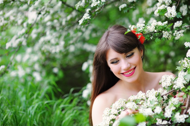 Glückliche junge Frau in einem Frühlingspark, der die Blumen riecht