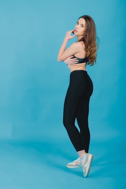 Glückliche junge Frau in lächelnder Sportkleidung Muskulöses Fitness-Modell auf blauem Hintergrund