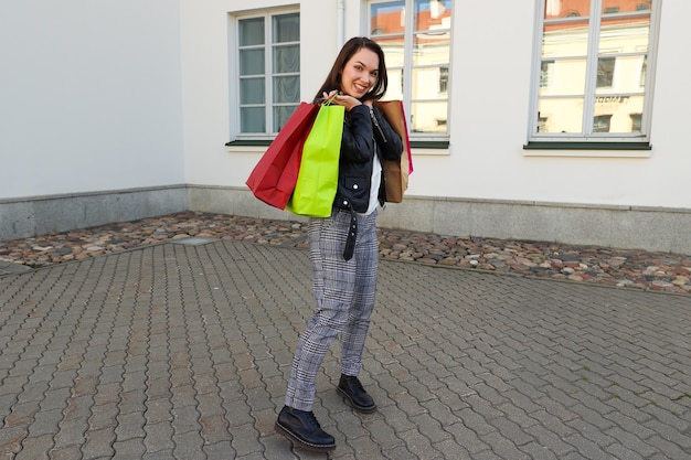 Glückliche junge Frau mit bunten Taschen geht nach dem Einkaufen