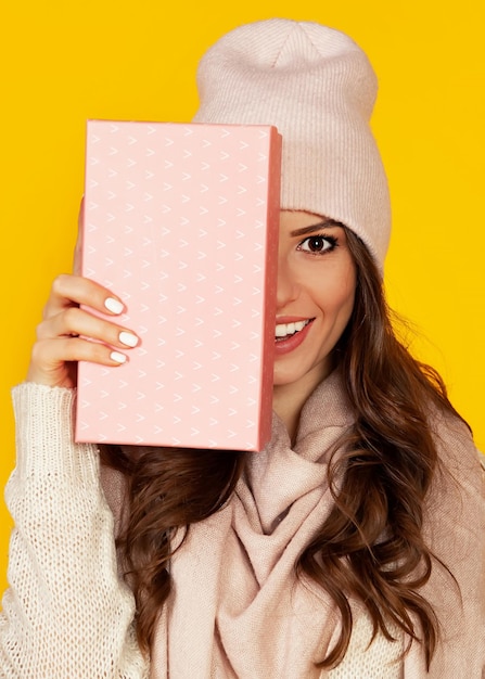 Glückliche junge Frau mit einer Geschenkbox in den Händen bedeckt die Hälfte von h
