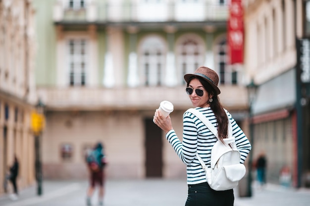Glückliche junge Frau mit Hut auf der Straße der europäischen Stadt