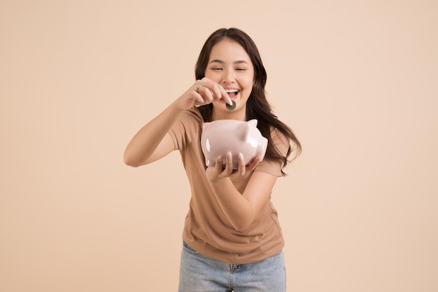 Glückliche junge Frau mit Sparschwein im Studio