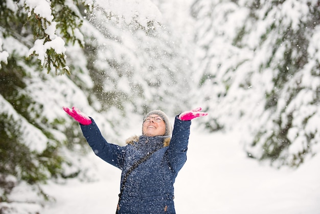 Glückliche junge Frau spielt mit einem Schnee am sonnigen Wintertag