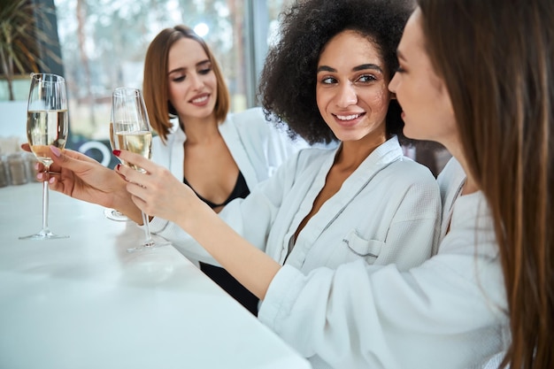 Glückliche junge Frauen, die Champagner stehen und halten