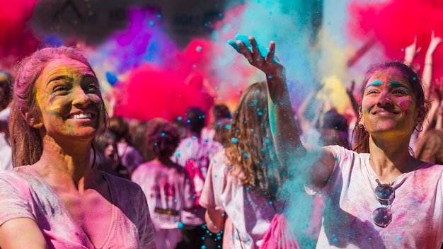 Glückliche junge Frauen, die mit holi Farben spielen