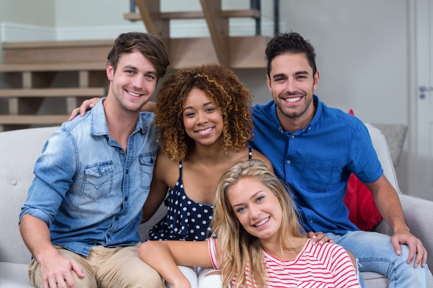 Glückliche junge Freunde, die auf Sofa sitzen