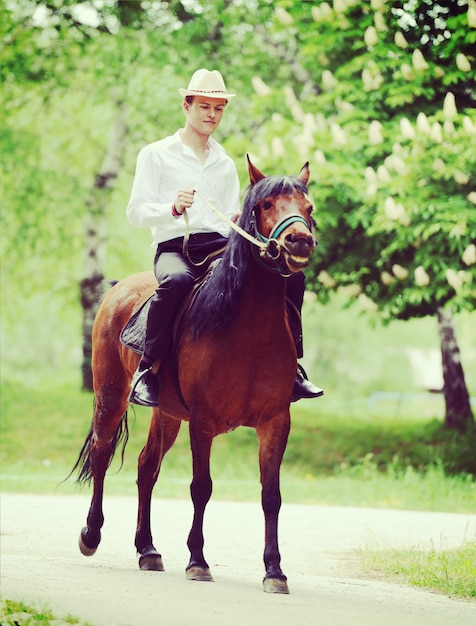 Glückliche junge Leute auf Landschaft mit Pferd für das Reiten