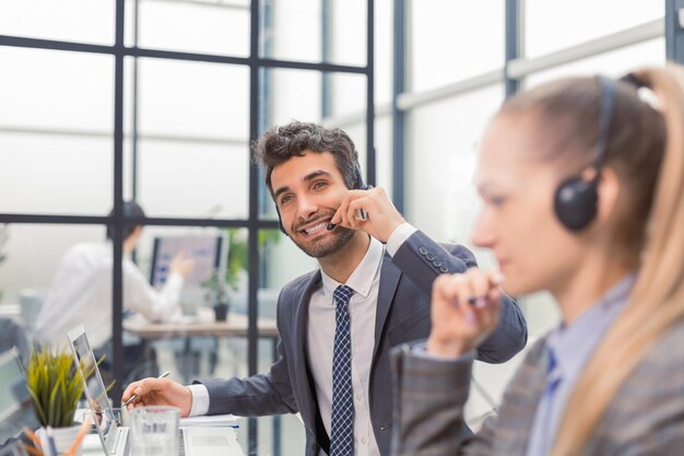 Glückliche junge männliche Kundenbetreuerin, die im Büro arbeitet