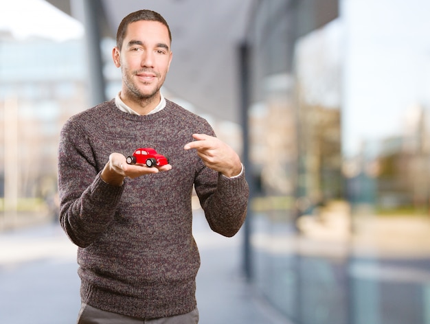 Foto glückliche junge mann hält ein spielzeugauto