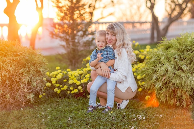 Glückliche junge Mutter, die Spaß mit ihrem Kind im sonnigen Sommertag hat Familienlebensstil