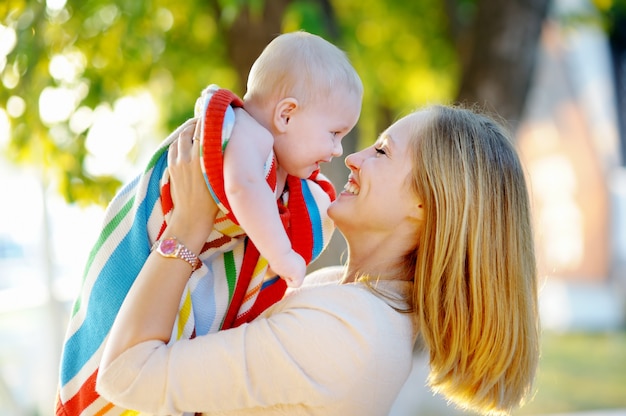 Glückliche junge Mutter mit ihrem kleinen Baby in einem Sonnenuntergang