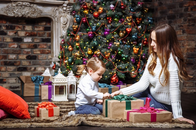 Glückliche junge Mutter und Tochter mit Weihnachtsgeschenken