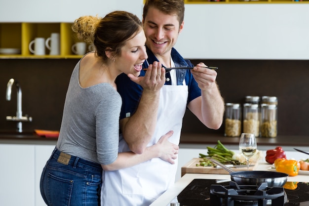 Glückliche junge Paar kocht zusammen in der Küche zu Hause.
