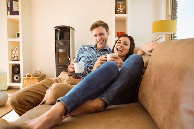 Glückliche junge Paare, die auf der Couch sich entspannen