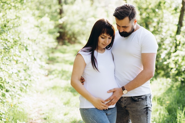 Glückliche junge Paare, die Baby im Sommerpark erwarten