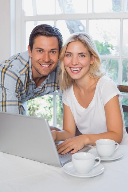 Glückliche junge Paare mit Laptop zu Hause