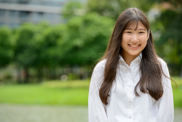 Glückliche junge schöne asiatische Teenagerfrau im Park