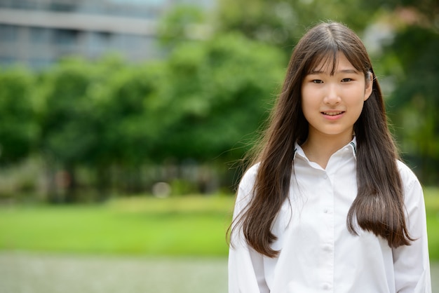 Glückliche junge schöne asiatische Teenagerfrau im Park