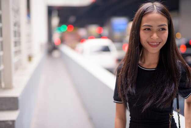 Glückliche junge schöne asiatische Touristenfrau, die in den Stadtstraßen denkt