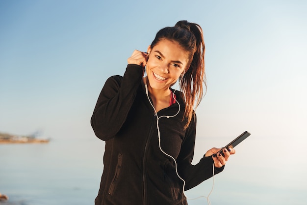 Glückliche junge Sportlerin, die Musik hört