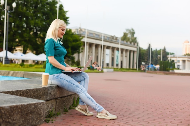 glückliche junge studentin mit laptop in der stadtparkstudie