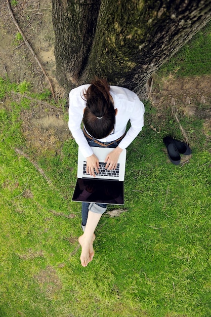 glückliche junge studentin mit laptop in der stadtparkstudie