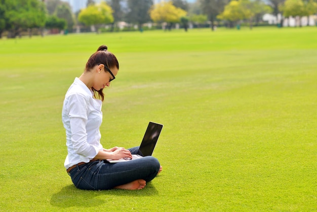 glückliche junge studentin mit laptop in der stadtparkstudie