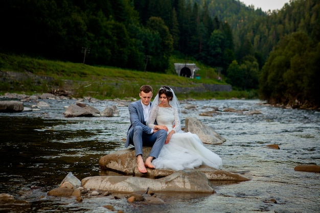 Glückliche Jungvermählten, die auf dem Fluss stehen und lächeln. Flitterwochen, Foto zum Valentinstag.