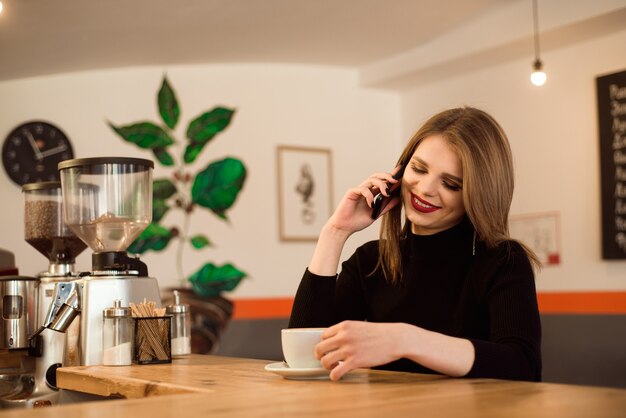 Glückliche kaukasische Frau, die ihr Foto am Handy beim Entspannen im Café während der Freizeit beobachtet.