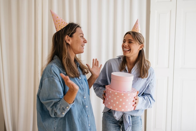 Glückliche kaukasische frau erhält weihnachtsgeschenk von ihrer freundin, feiert geburtstag zu hause. Lifestyle, verschiedene Emotionen, Freizeitkonzept.