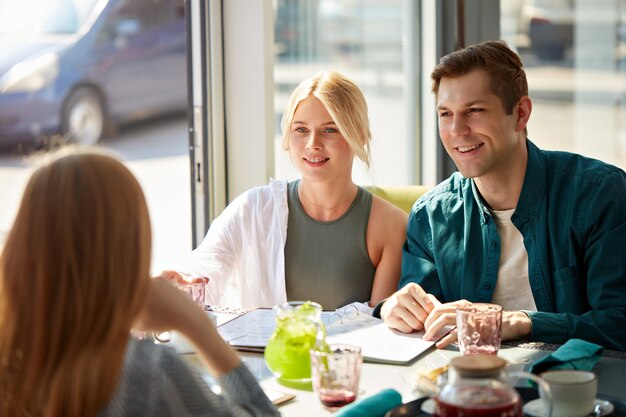 Glückliche kaukasische Freunde ruhen sich im Café aus, essen und Spaß