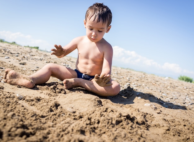 Glückliche Kinder auf den Sommerstrandsandferien, die Spaß und glückliche Zeit haben