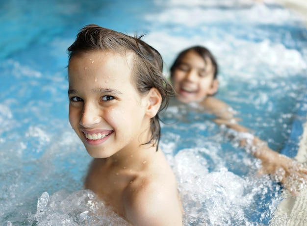 Glückliche Kinder, die auf SommerSwimmingpool genießen