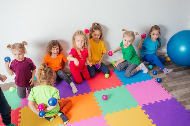 Glückliche Kinder, die Bälle in Plastikkorb werfen