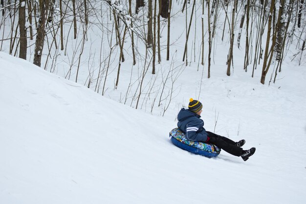 Glückliche Kinder, die im Winter die Schneerutsche hinunterfahren. fröhliche kinder aktive sport wintererholung. Eisbergskifahren