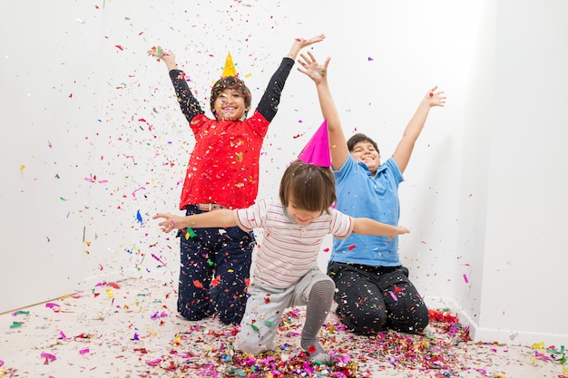 Glückliche Kinder, die Party mit Schlagkonfettis feiern