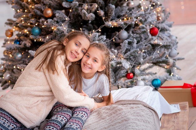 Glückliche kinder, die spaß haben und geschenke nahe weihnachtsbaum öffnen.