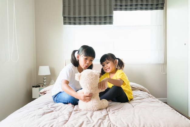 Glückliche Kinder, die zusammen im Schlafzimmer spielen