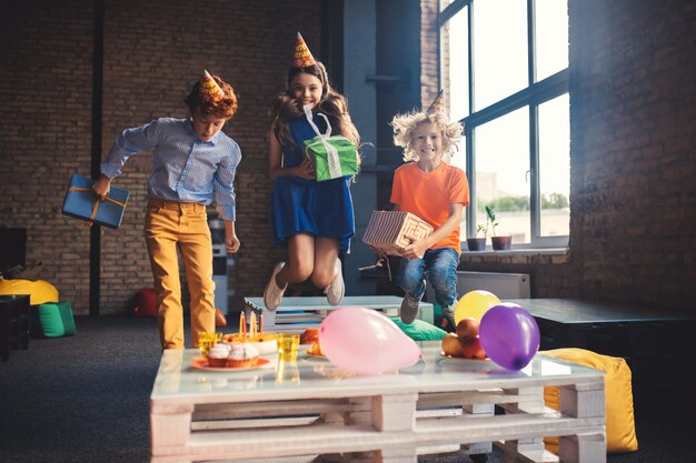 Glückliche Kinder. Drei Freunde in bday Hüten springen und sehen glücklich aus