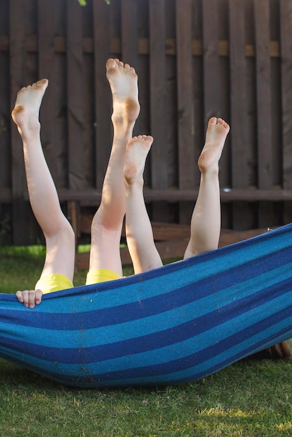 Glückliche Kinder entspannen in einer Hängematte im Freien Kinderfüße barfuß Urlaub Urlaub