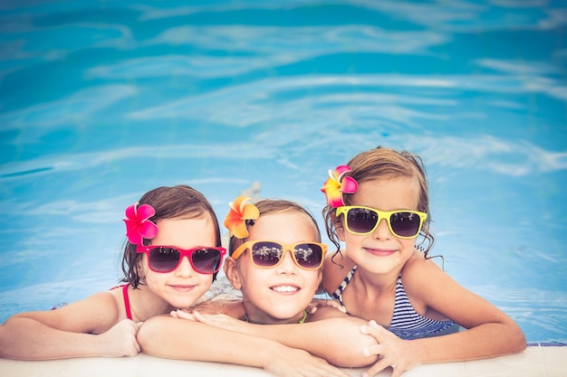 Glückliche Kinder im Schwimmbad Lustige Kinder, die im Freien spielen Sommerurlaubskonzept