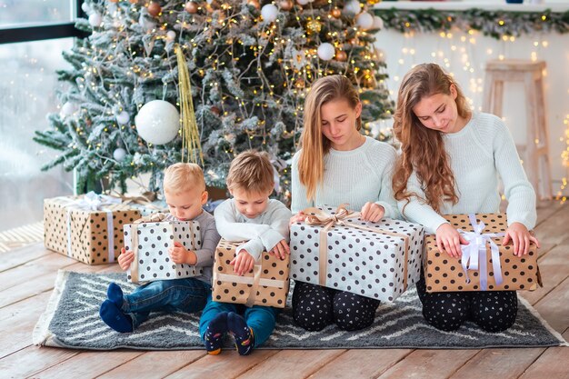 Glückliche Kinder in der Nähe des Weihnachtsbaums mit den Geschenkboxen