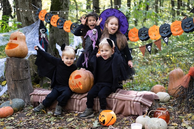 glückliche kinder in halloween-kostümen, die spaß in halloween-dekorationen im freien haben