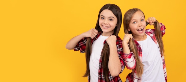 Glückliche Kinder in lässig kariertem Hemd halten langes glattes Haar auf gelbem Hintergrundhaar Kindermädchen