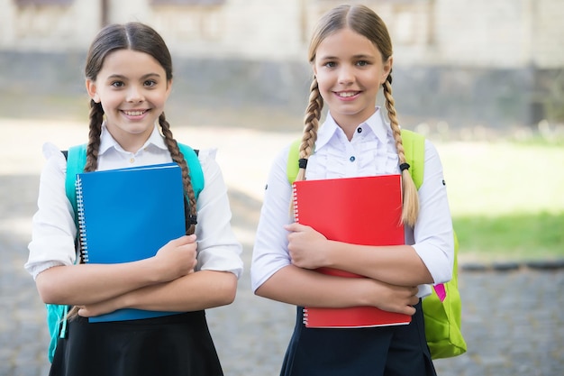 Glückliche Kinder in Schuluniformen halten Studienbücher im Freien, Entwicklung.